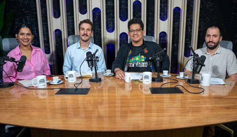 Quatro pessoas num estúdio de gravação sorrindo para o fotógrafo