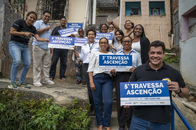 Pessoas segurando a placa de uma rua em Salvadona comunidade 