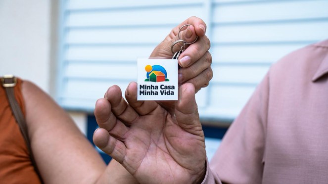 Na foto mãos segurando as chaves de uma das unidades habitacionais