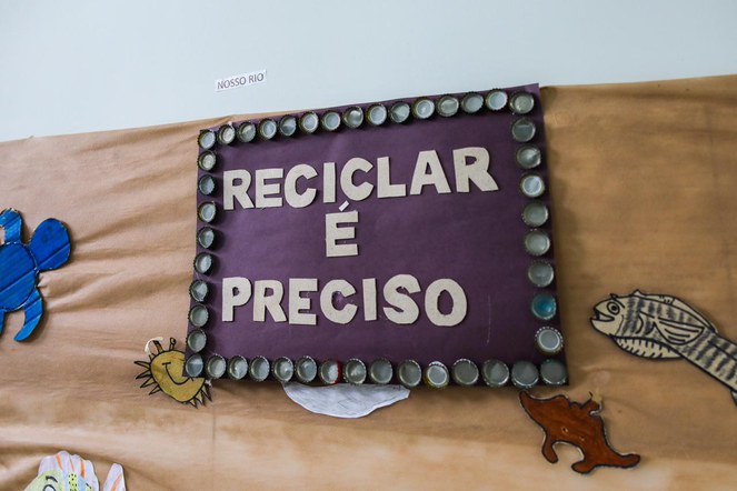 Na imagem, painel com a frase Reciclar é preciso