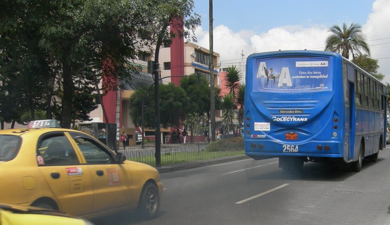Na imagem, um carro táxi e um ônibus do transporte público