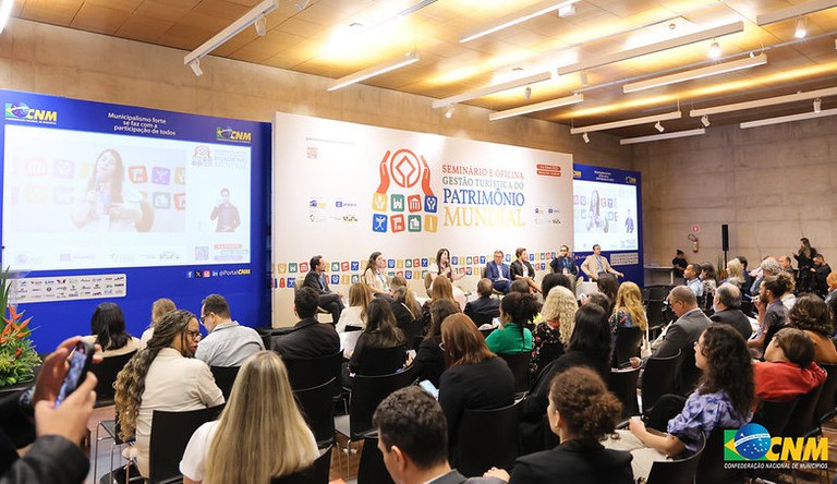 Na imagem, pessoas reunidas em auditório