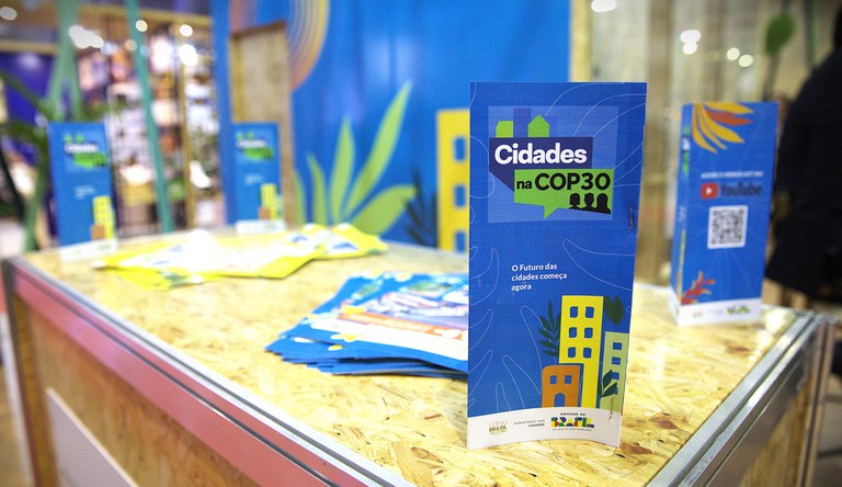 Na imagem, folheto com a frase Cidades na COP30