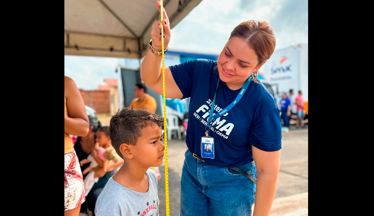 Na foto mulher medindo a altura de uma criança