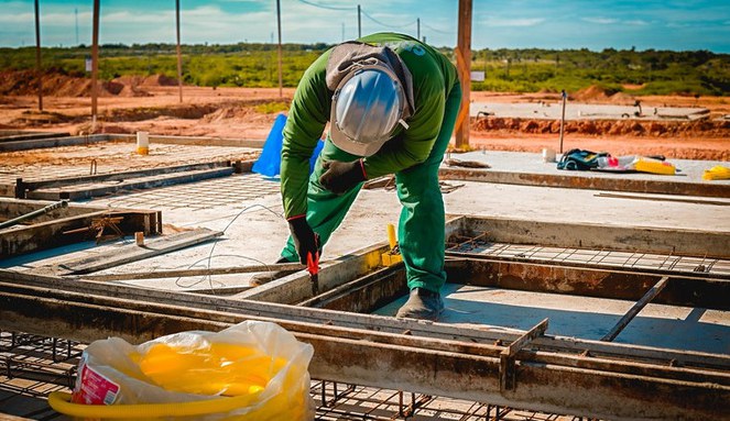 Entenda as razões do sucesso do Minha Casa, Minha Vida em 2025 Na imagem, pedreiro trabalhando em obra de prédios habitacionais