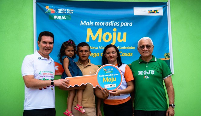 Na imagem ministro Jader Filho ao lado de família segurando chave da casa própria
