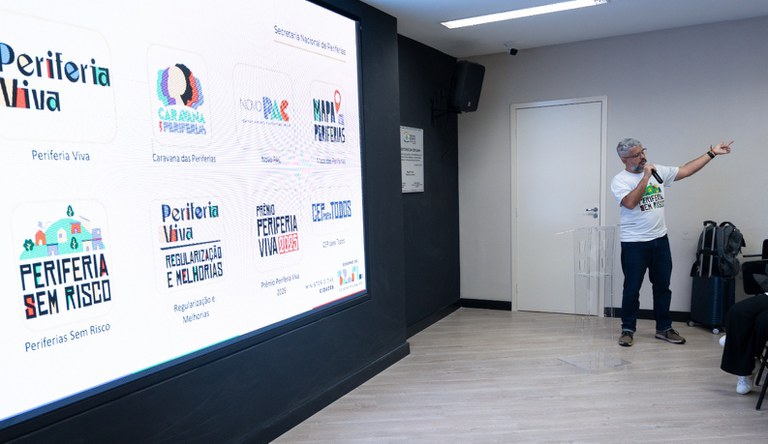 Na imagem homem segura microfone durante apresentação sobre dados de periferias no Brasil