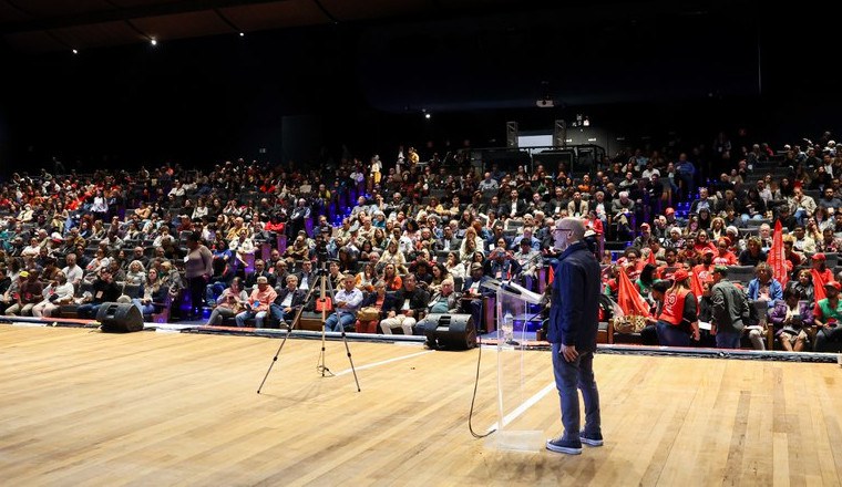 Na imagem homem fala para plateia sentada