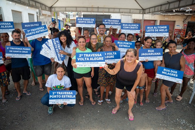 Na imagem moradores posam para foto com placas de CEP´s. 