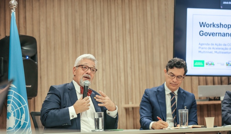 Na imagem dois homens sentados durante reunião sobre mudanças climáticas