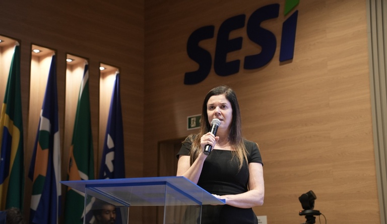 Na imagem fala ao microfone para plateia