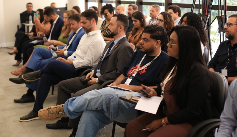 Na imagem pessoas sentadas assistindo uma palestra