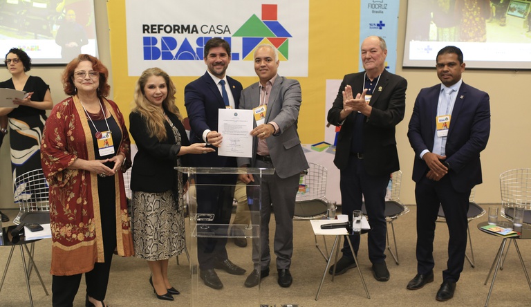 Secretários Executivo, Vladmir Lima, e de Habitação, Augusto Rabelo exibem documento junto a autoridades