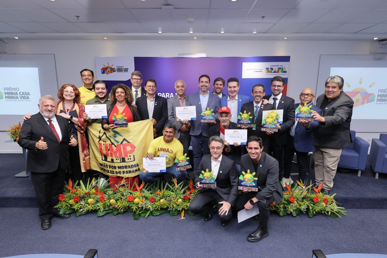 Na imagem ministro Jader Filho posa para foto com ganhadores do prêmio Minha Casa, Minha Vida