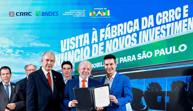 Na imagem presidente Lula ao lado do ministro Jader seguram contrato de investimento no transporte público de SP.