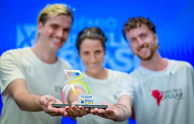 Três dos vencedores exibindo um dos troféus