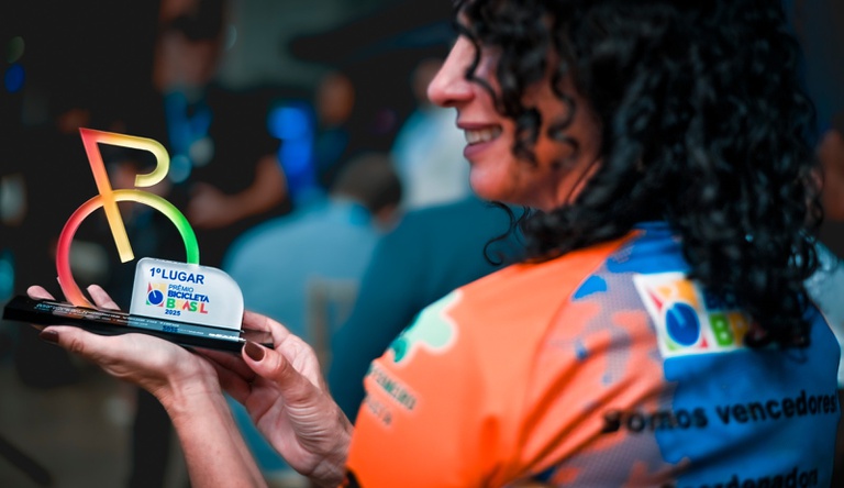 Na imagem mulher segurando prêmio símbolo de bicicleta