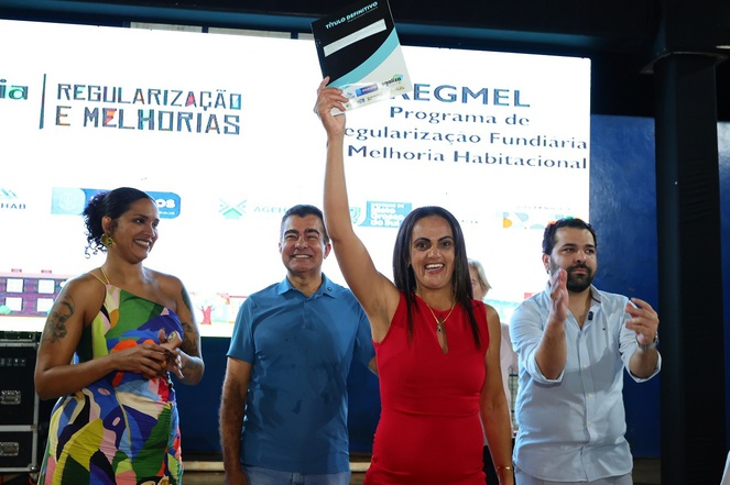 Na imagem há dois homens e duas mulheres, uma delas levanta documento de posse de terra.