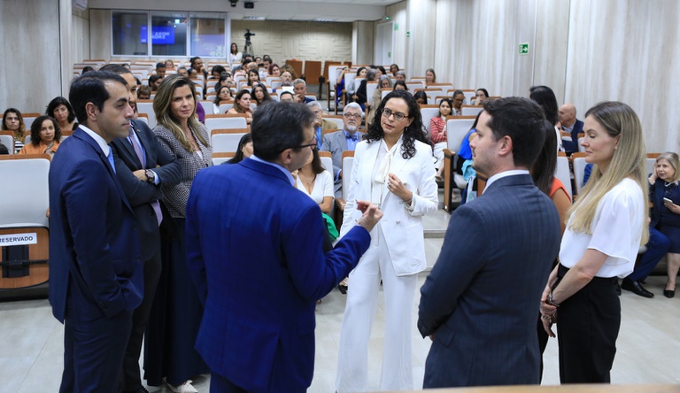Na imagem pessoas reunidas numa roda de conversa, ao fundo plateia sentada.