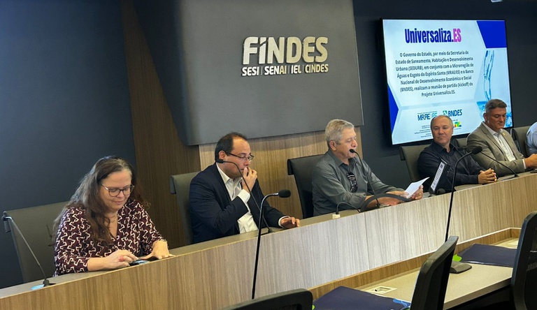 Na imagem quatro homens e uma mulher sentados durante apresentação sobre saneamento