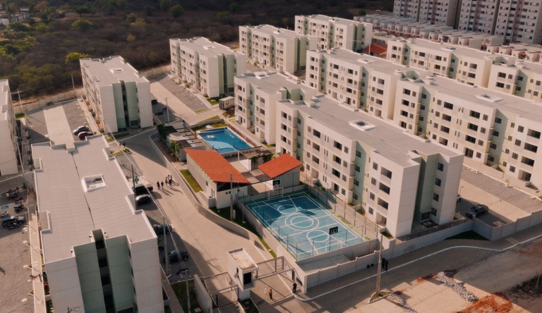 Na imagem foto aérea de prédio residencial com quadra poliesportiva