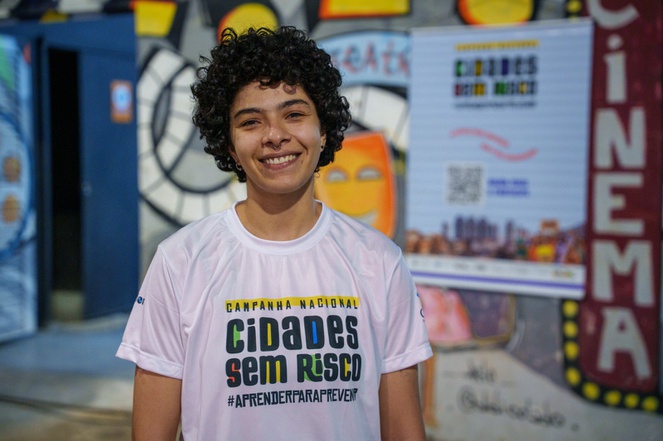 Na imagem adolescente vestindo blusa da campanha Cidades sem Risco posa para foto