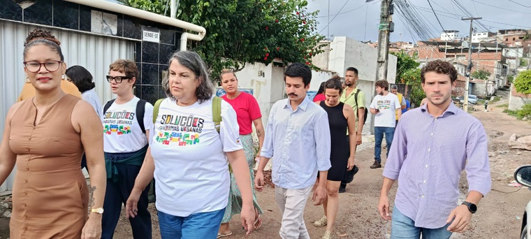 Na imagem quatro pessoas andando na rua de comunidade de Jaboatão