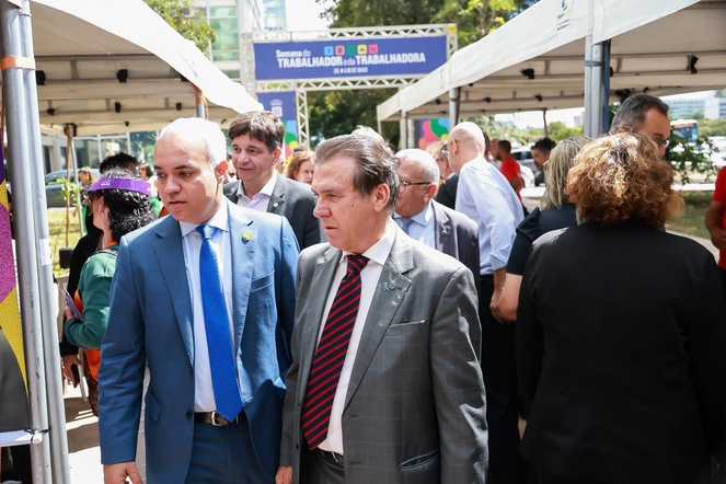 Na imagem dois homens andam pelos estandes da semana do trabalhador.