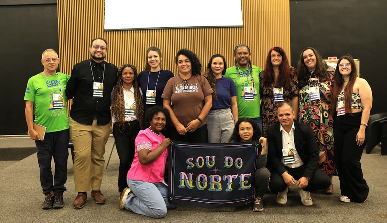 Na imagem pessoas posam para foto com bandeira com a frase sou do norte