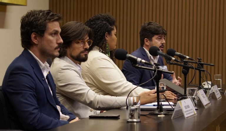 Na imagem três homens e uma mulher participam de debate na Câmara dos Deputados