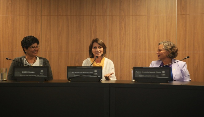 Ministério das Cidades é reconhecido por avanço em integridade pública Na imagem três mulheres sentadas, uma delas segura fala ao microfone para plateia.