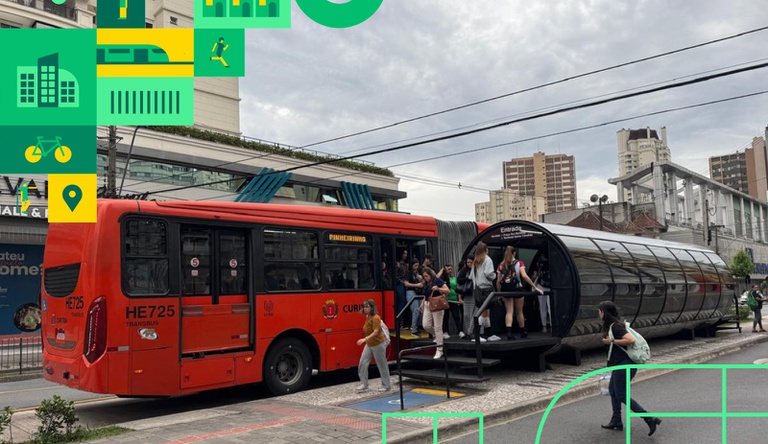 Na imagem ônibus passando numa avenida, ao fundo pessoas andando