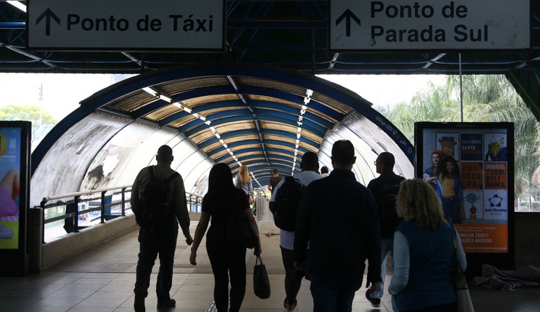 Na imagem pessoas andando numa estação de metrô