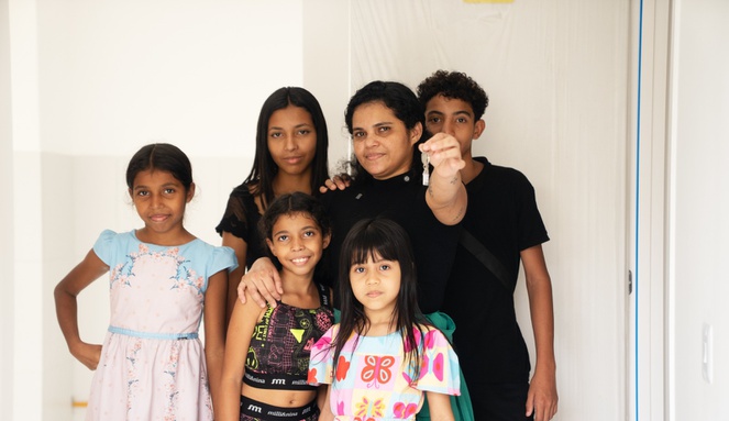 Na imagem família posa para foto em frente da sua nova casa