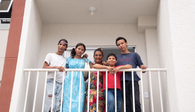 Na imagem família na varanda de casa