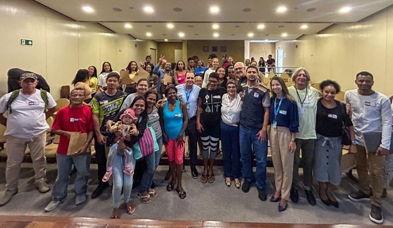 Na imagem famílias posam para foto durante entrega de casas do minha casa minha vida