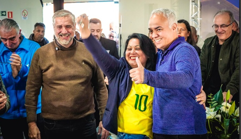 Na imagem ministro das cidades entrega chave de casa propria para mulher vestida com camisa da selecao brasileira