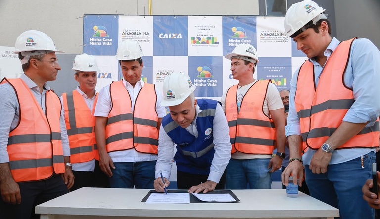 Na foto o ministro das cidades assina documento junto a autoridades