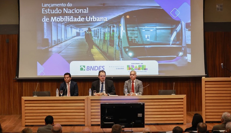 Na imagem pessoas discursam em evento