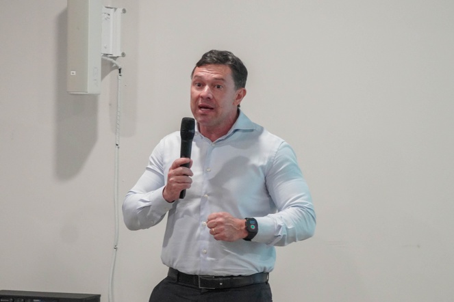 Na imagem homem discursa para plateia