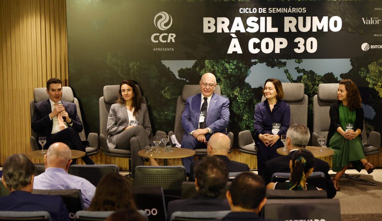 Na foto o ministro Jader Filho ao microfone ao lado de outras autoridades sentados a frente de um painel com os dizeres "Ciclo de Seminários Brasil Rumo a COP30"