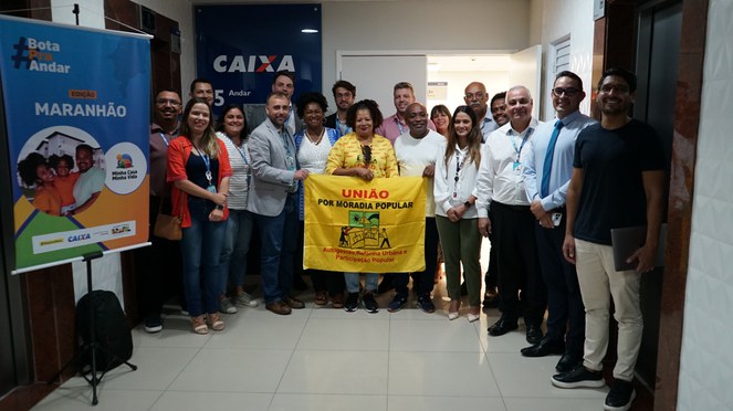 Na foto grupo de pessoas com cartaz com os dizeres