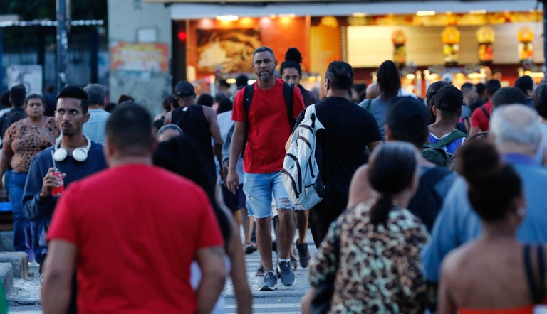 Na foto pessoas atravessando uma faixa de pedestres