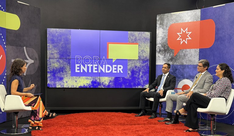 Grupo de pessoas sentadas conversando, ao fundo um telão.