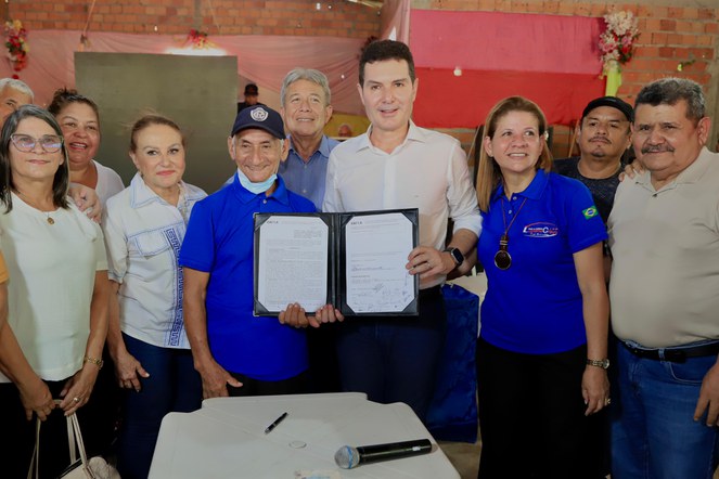 Na foto o ministro das cidades exibe documento entre diversas pessoas
