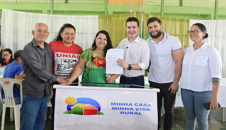 O ministro das Cidades exibe documento ao lado de quatro pessoas