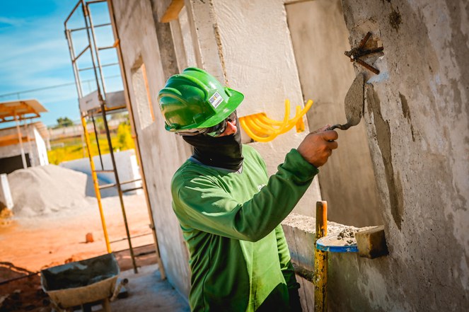 Na foto pedreiro trabalha em uma parede