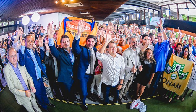 Na imagem há pessoas sorrindo com braço levantado.