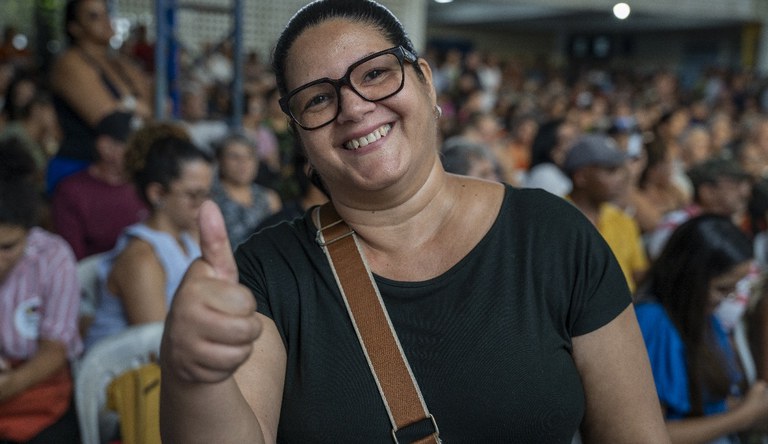 Mulher sorrindo apontado o dedo polegar para cima.