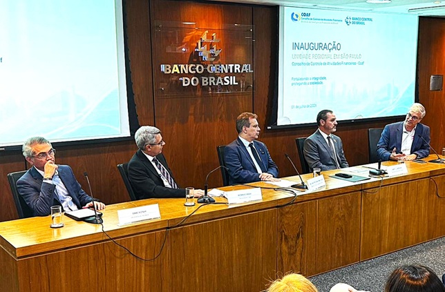 Homens brancos de terno em uma bancada de madeira tendo atrás o logotipo do Banco Central